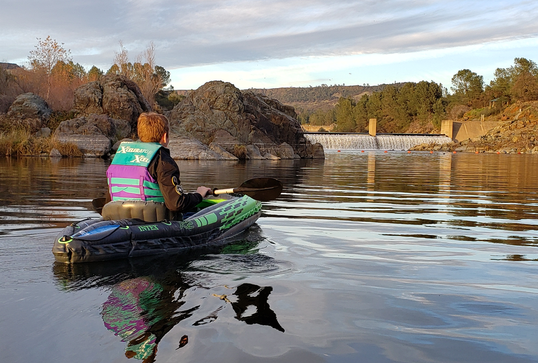 A person is rowing a kayak on a river.