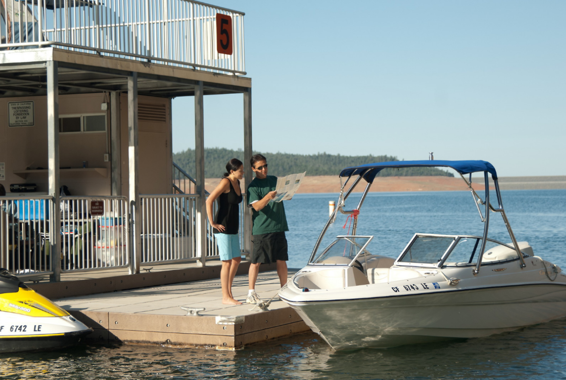 A man and a woman are standing next to a boat that says ' a ' on it