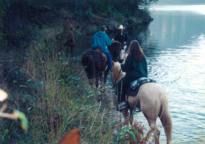 A group of people are riding horses across a river.