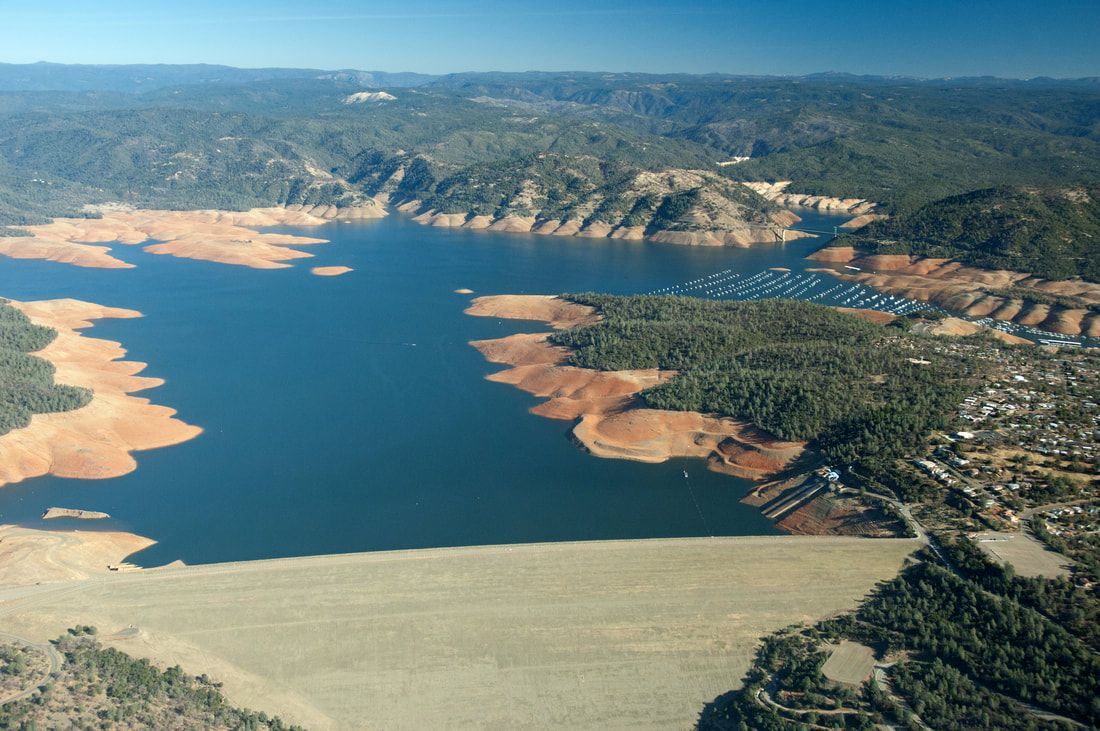 An aerial view of a large body of water surrounded by mountains and trees.