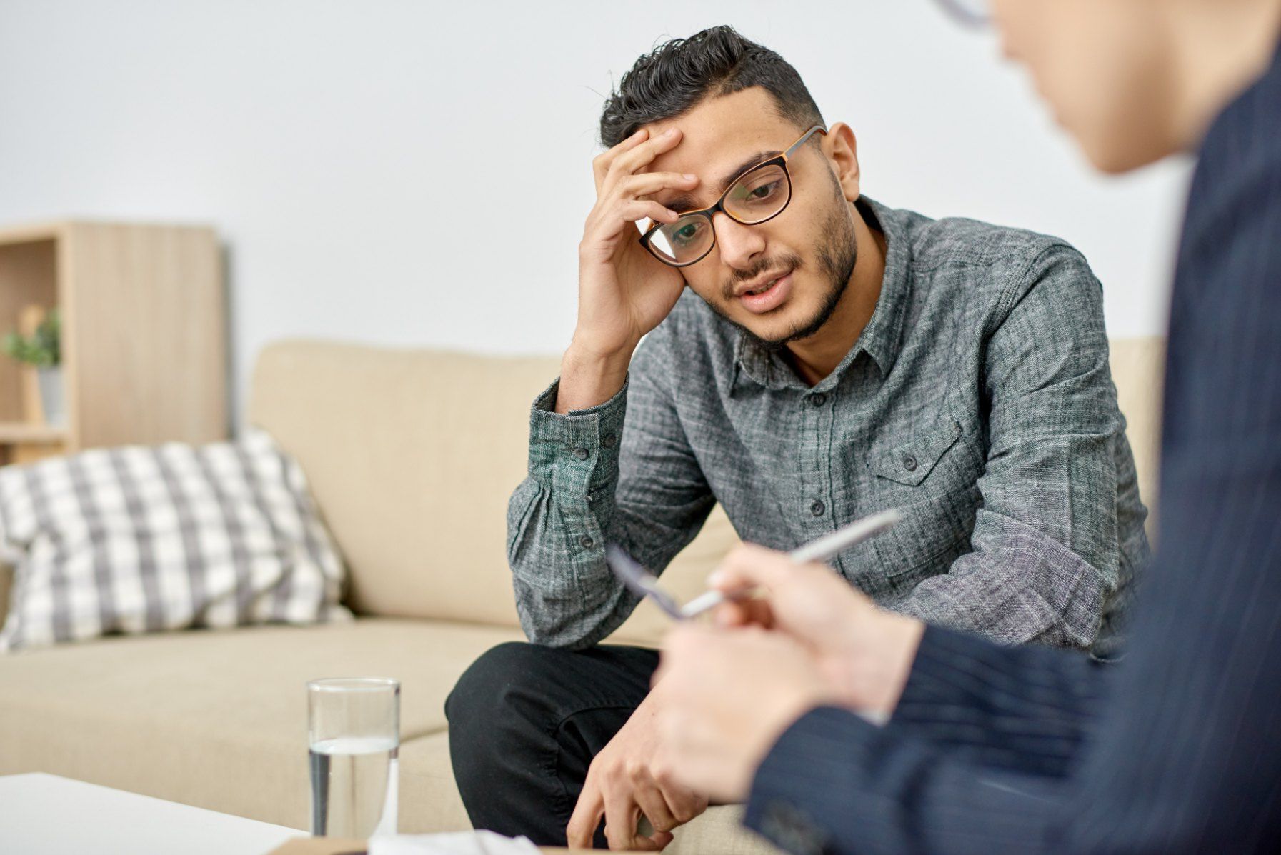 A man is sitting on a couch talking to a woman.