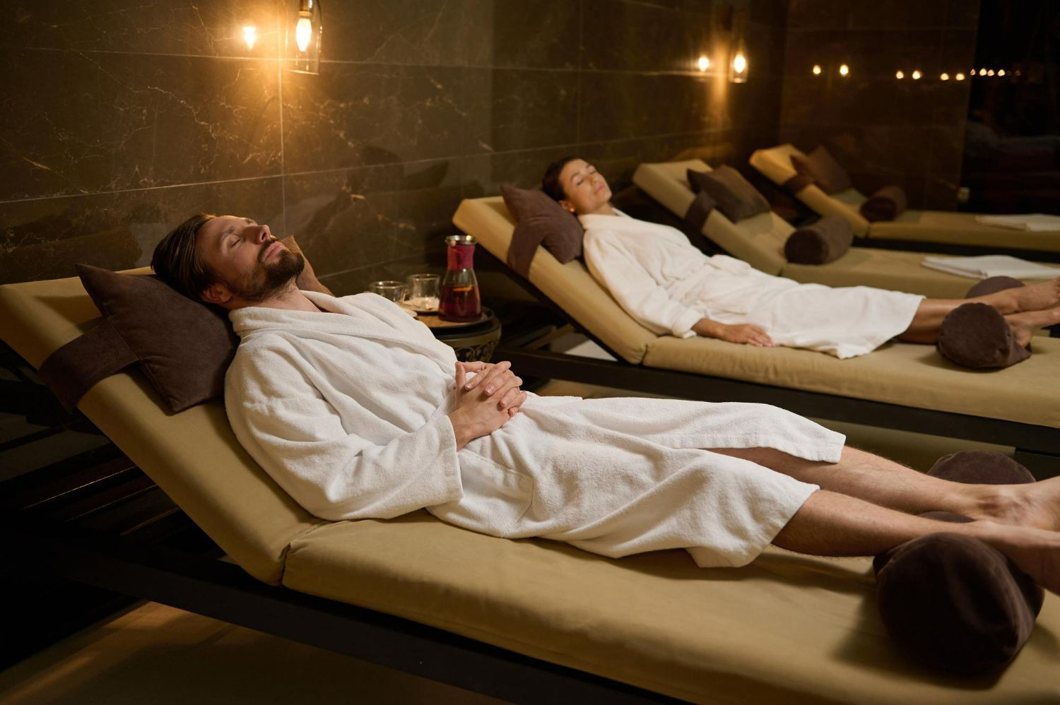 A man and a woman are laying on lounge chairs in a spa.