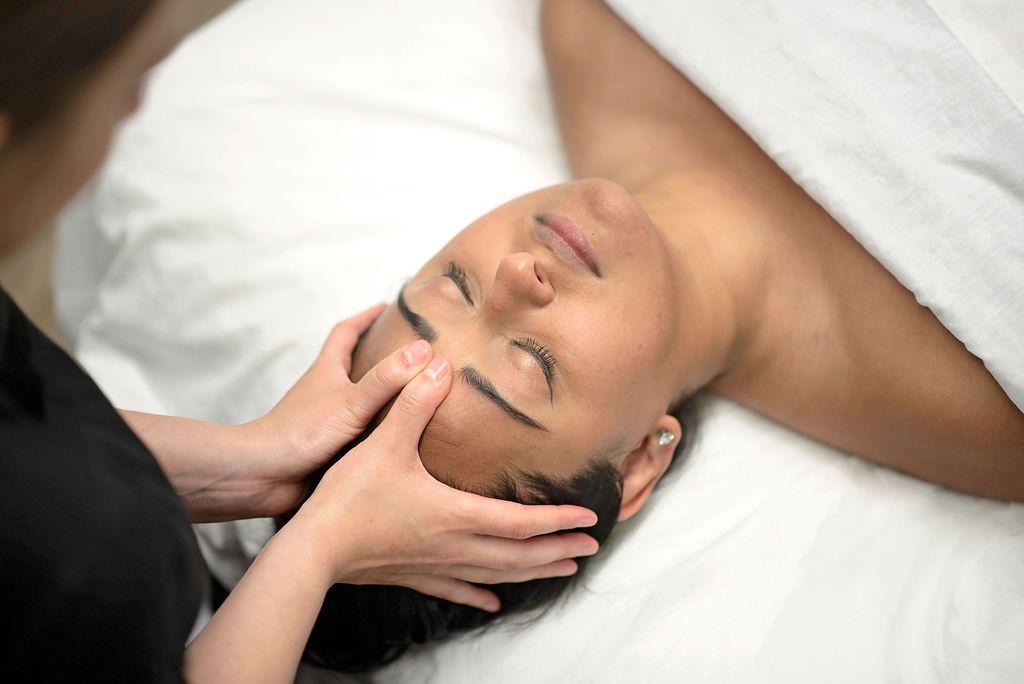 a woman laying on a bed getting a head massage