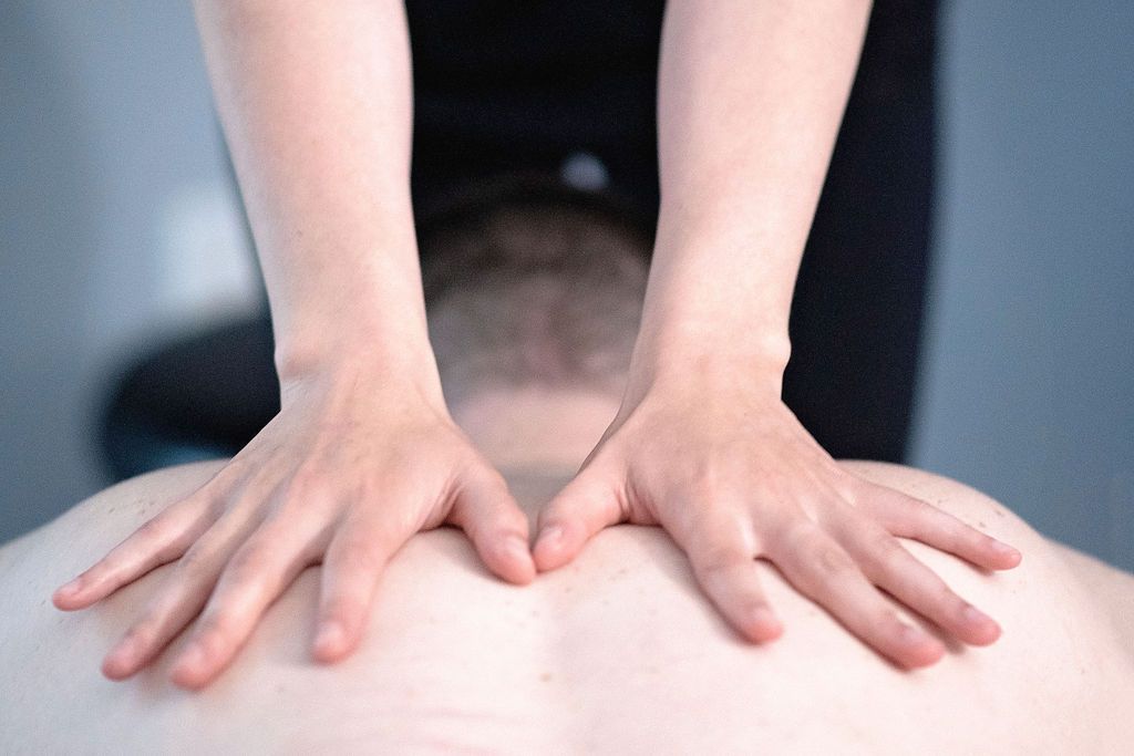 a person getting a massage with their hands on their back