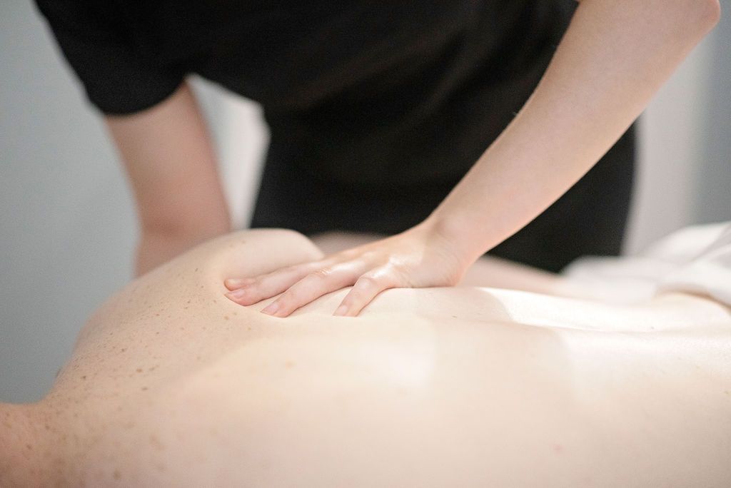 Person receiving back massage; therapist's hand on bare back.