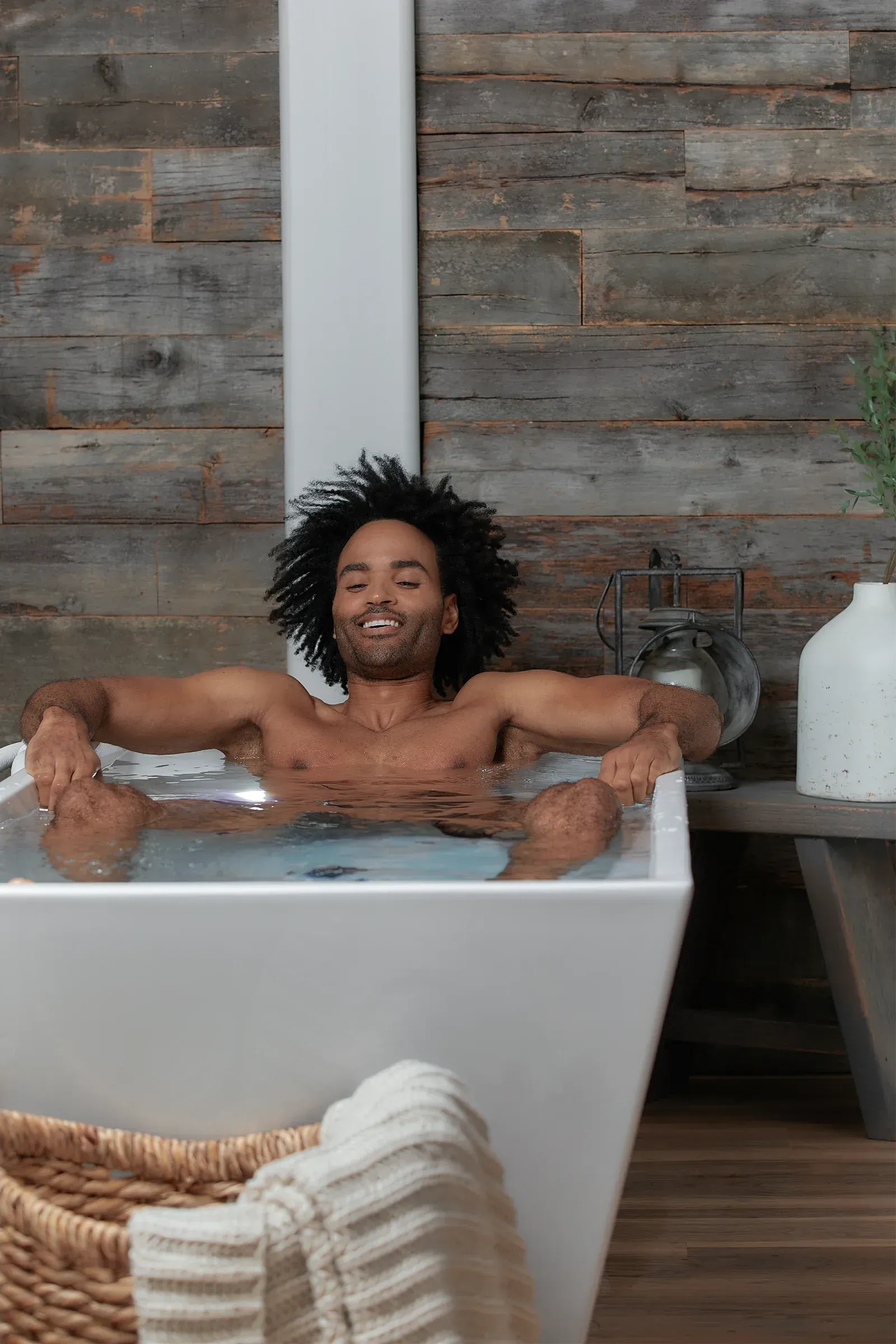 Person relaxing in an ice bath, smiling with eyes closed, surrounded by ice cubes