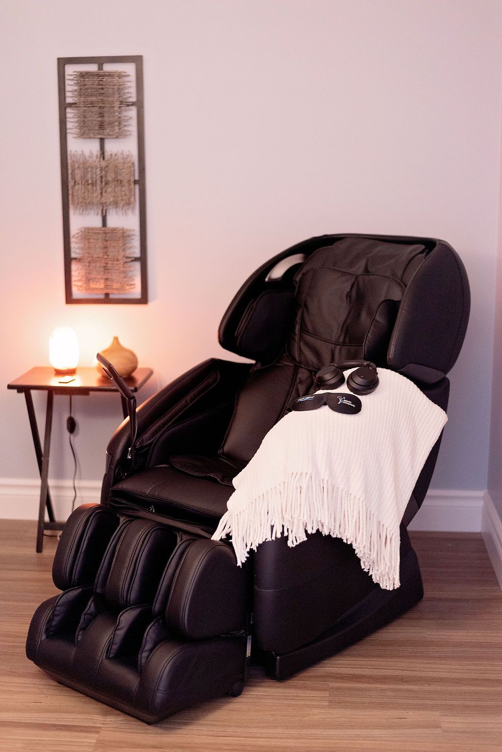 a black massage chair with a white blanket on it