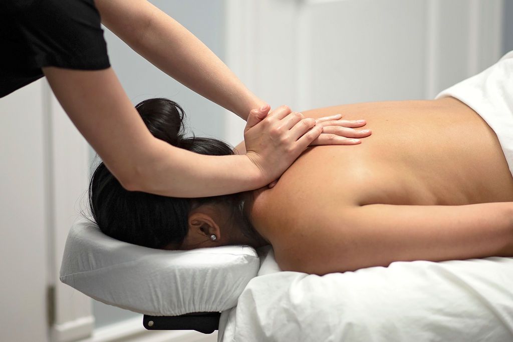 Person receiving back massage on a massage table, therapist's hands on back.