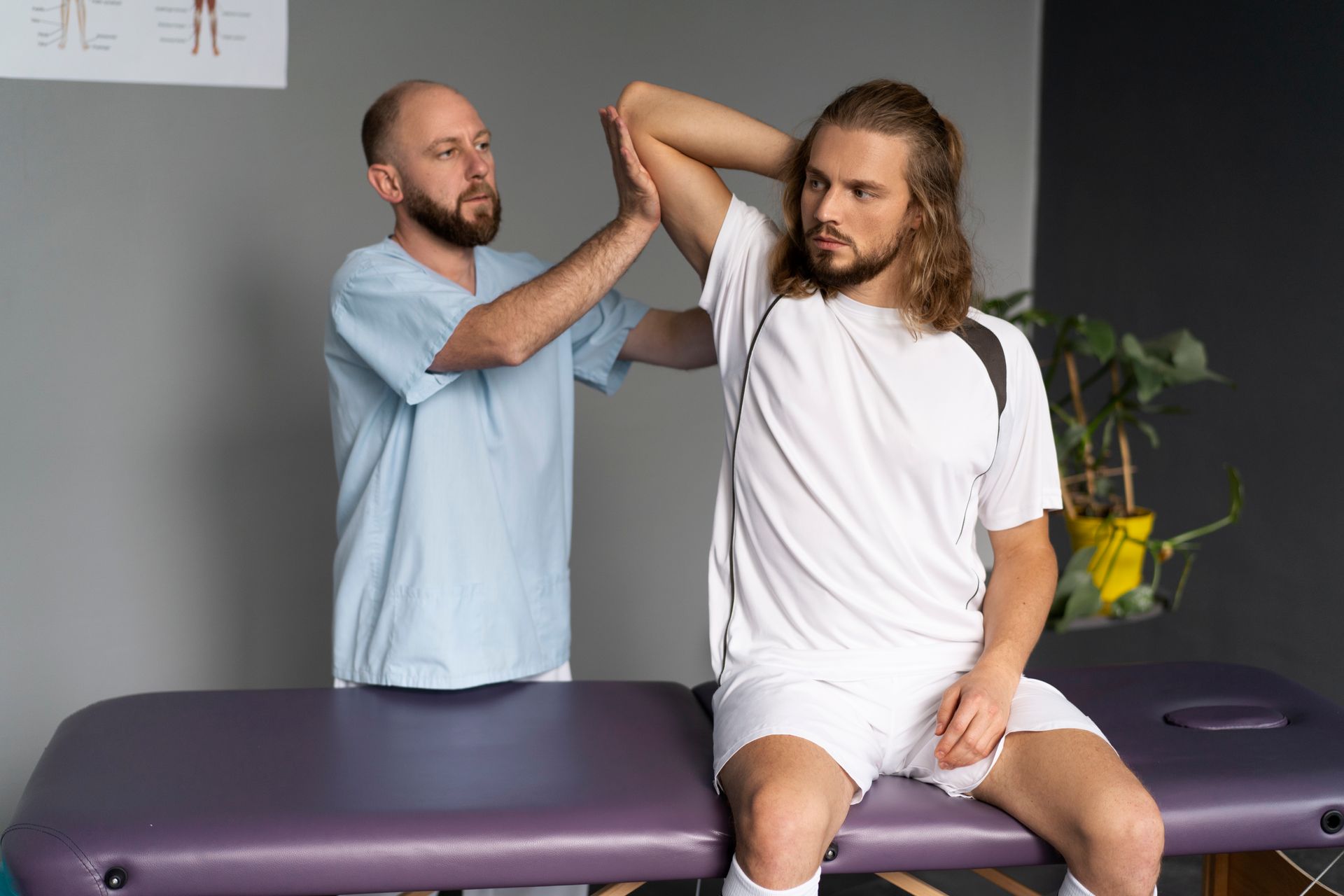 A man is sitting on a purple table getting a massage from a doctor.