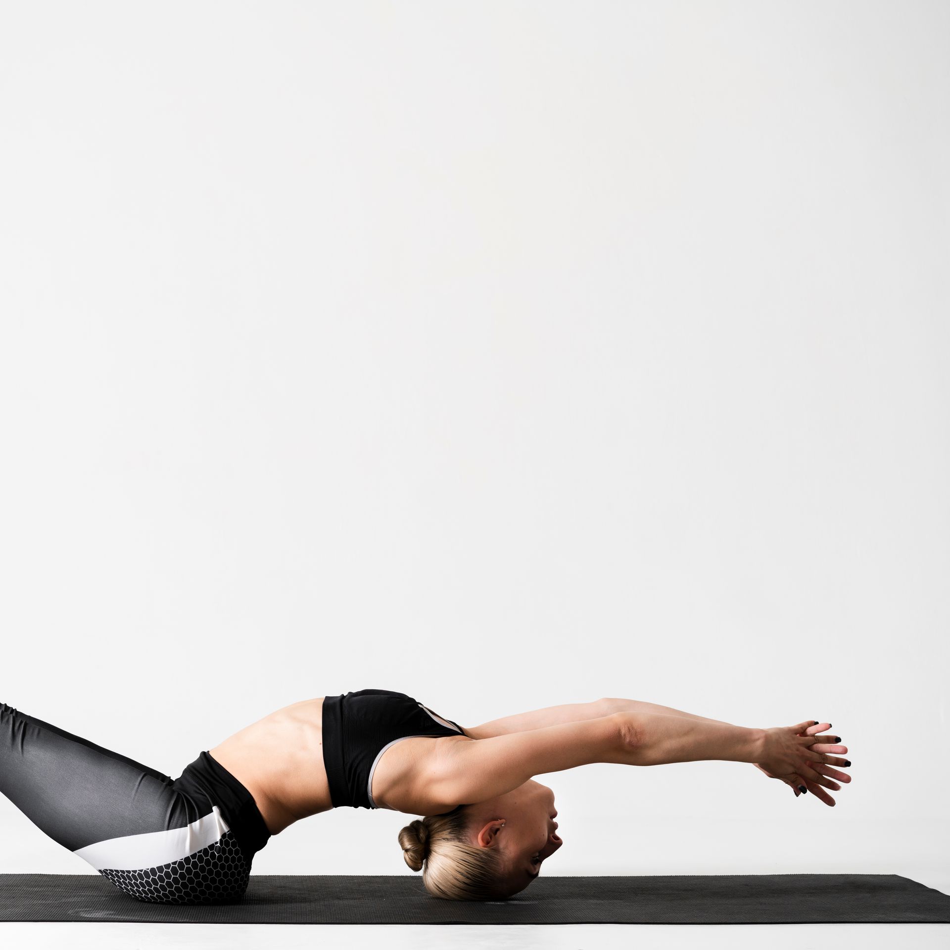 A woman is laying on her back on a yoga mat.