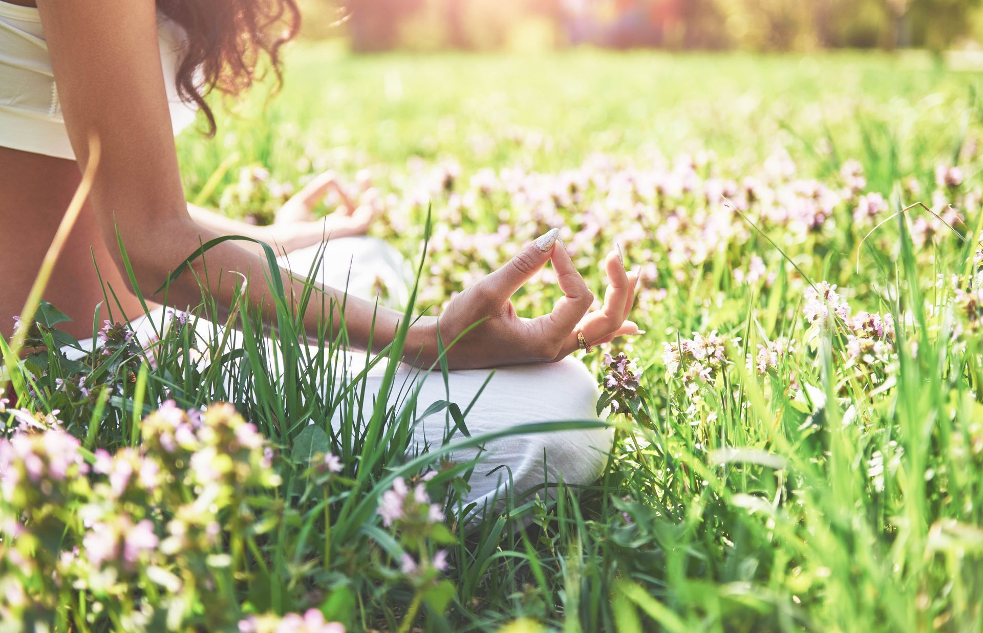 a woman sits in a lotus position in a field of flowers