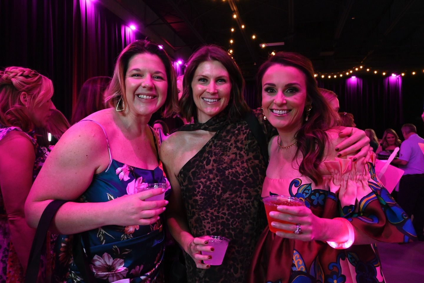 Three women are posing for a picture together at a party.