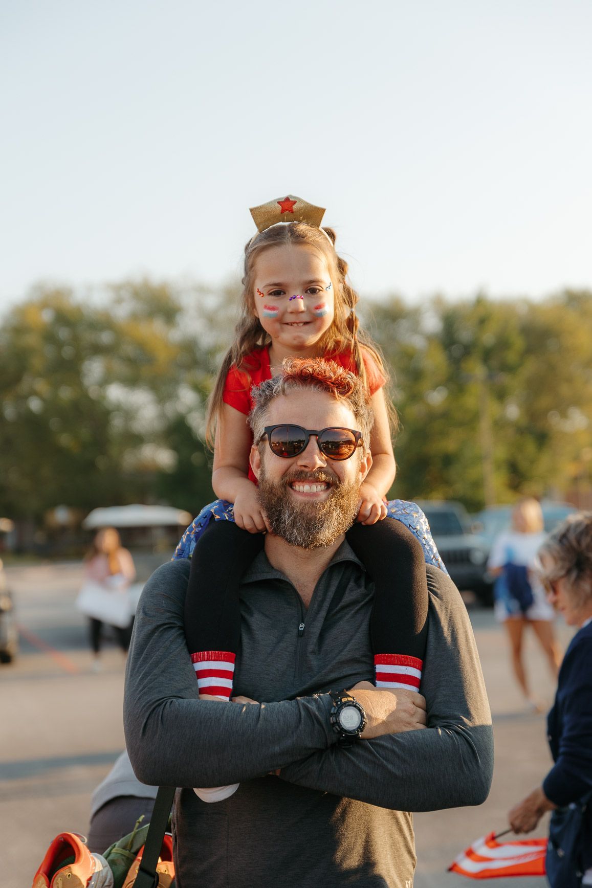 A little girl is sitting on a man 's shoulders.