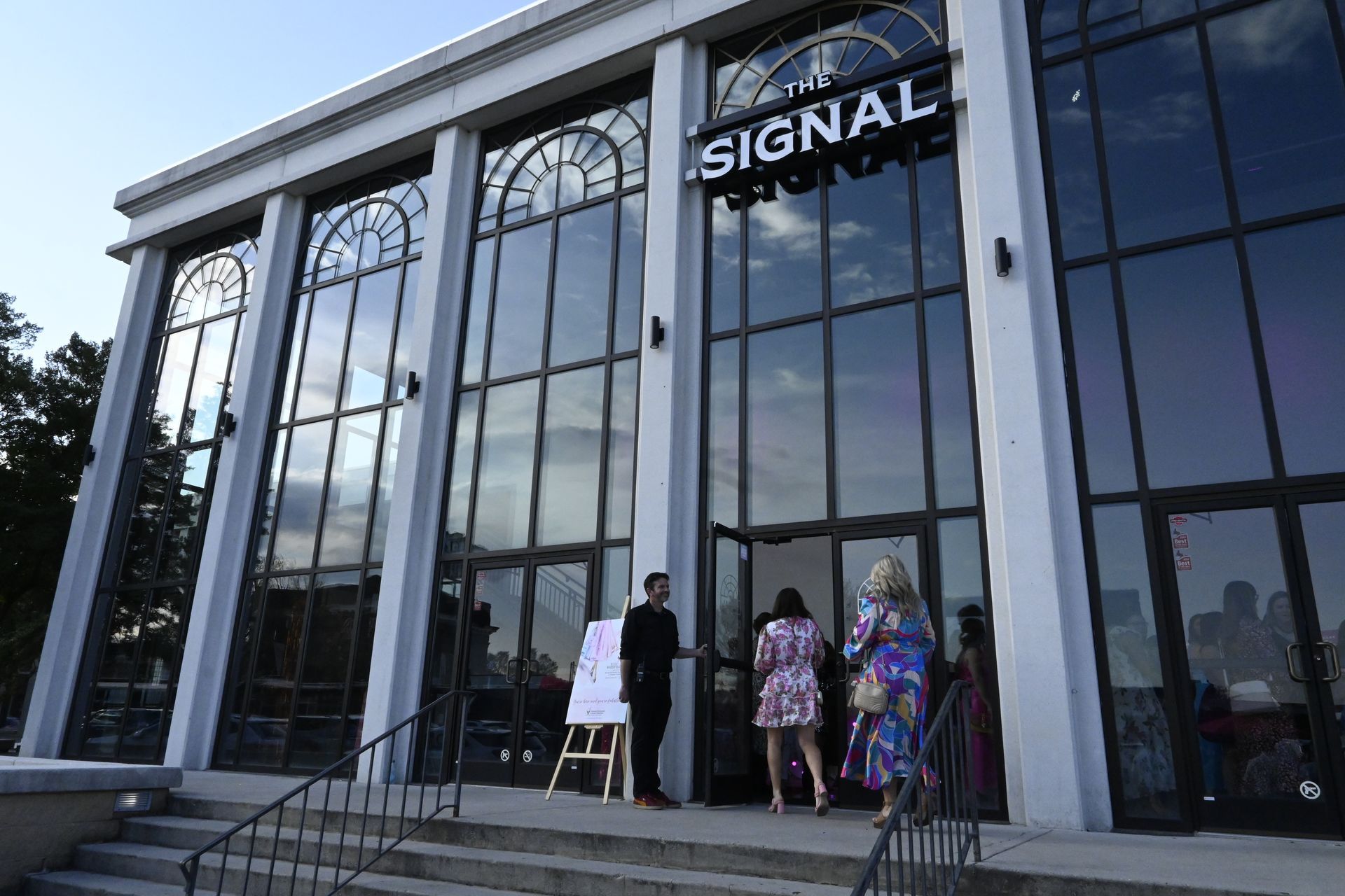 A woman in a sequined dress is sitting at a table with her hand up.