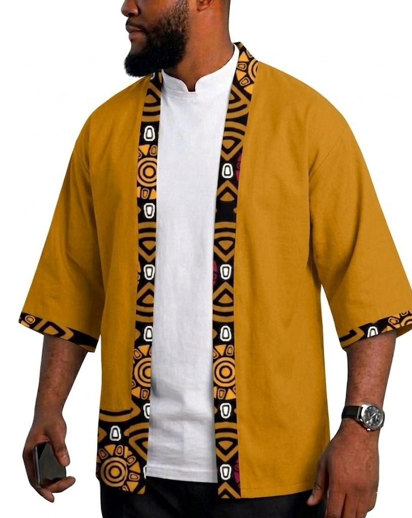 Una persona que viste un kimono amarillo mostaza abierto por delante, con ribetes de estampado geométrico en blanco y negro en los bordes y los puños.