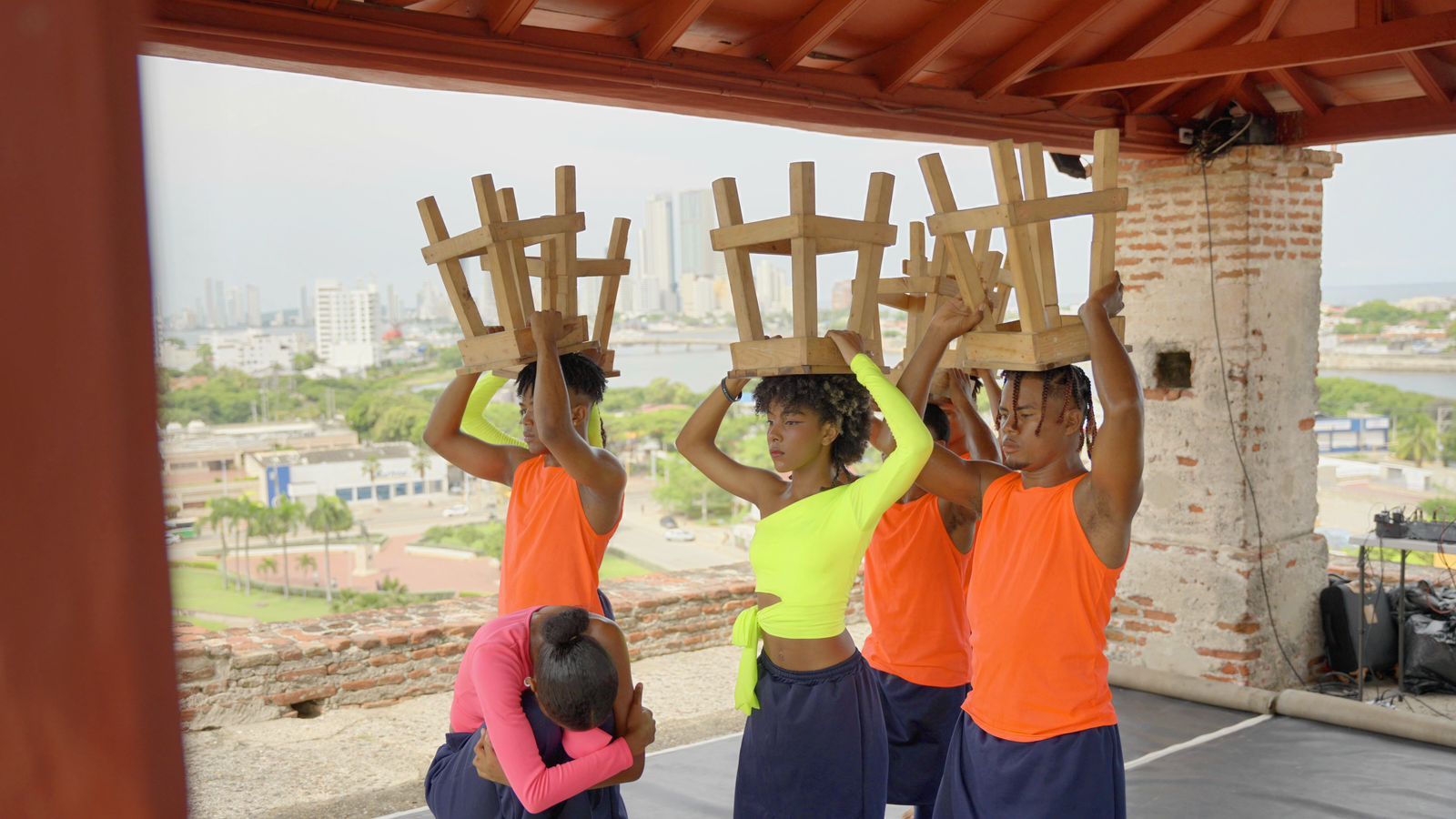 Un grupo de personas llevan sillas sobre sus cabezas.