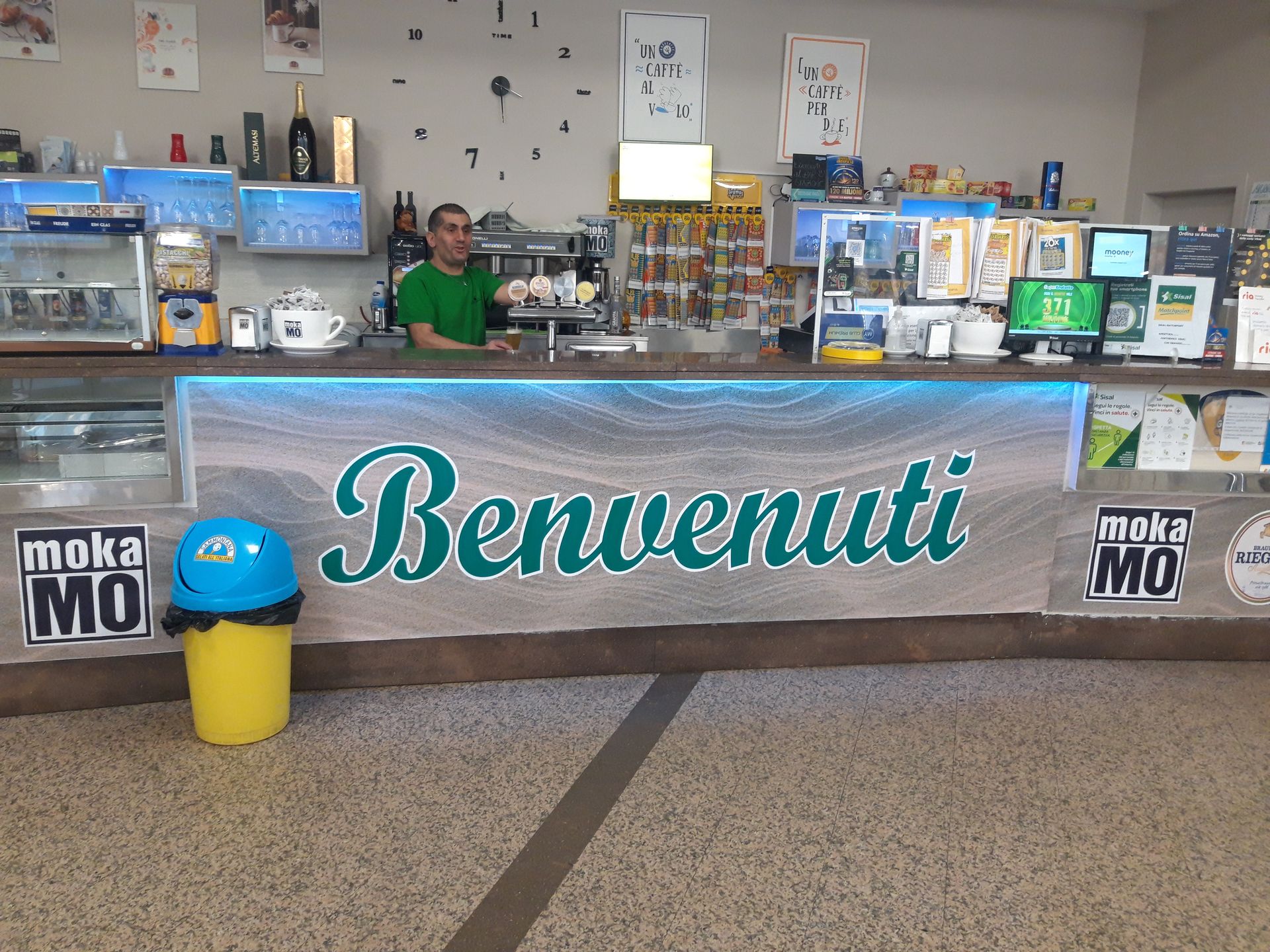 Un uomo sta dietro un bancone con la scritta benvenuti