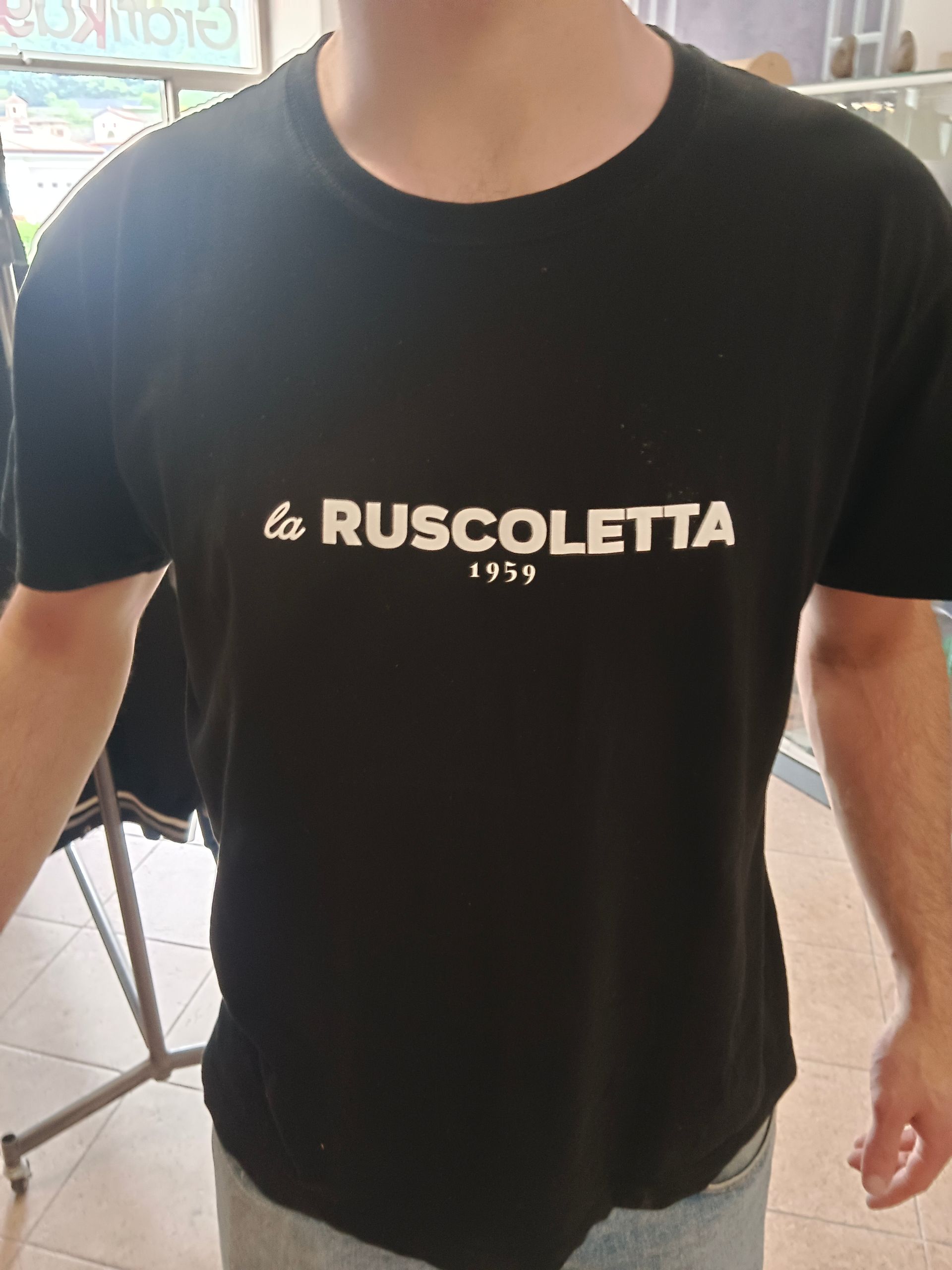 Un uomo indossa una maglietta nera con la scritta ruscoletta sopra
