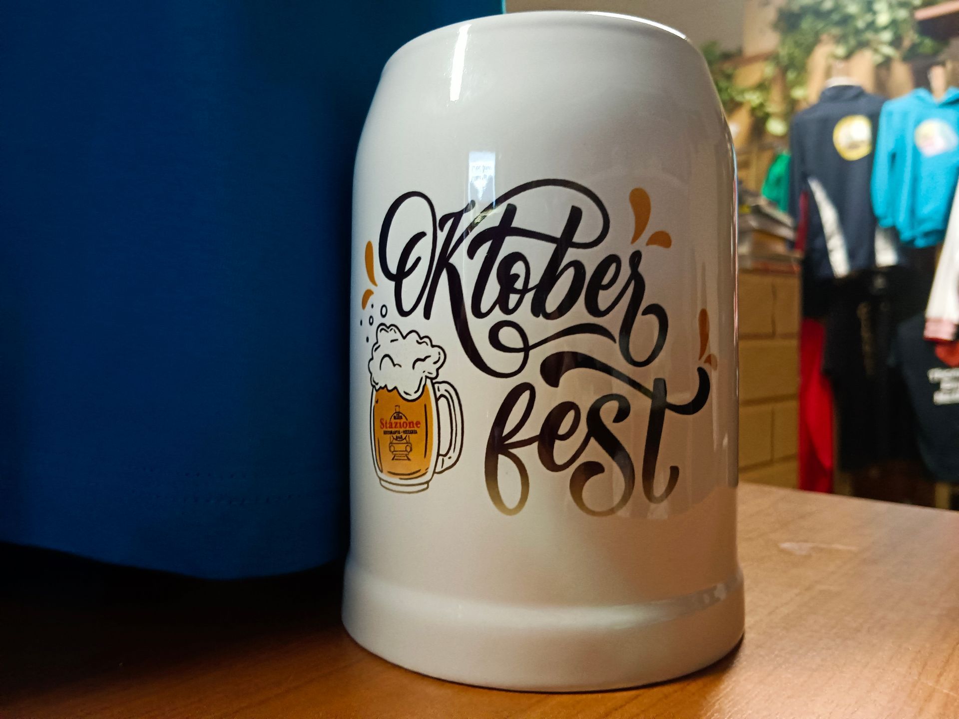 Una tazza bianca con la scritta Oktoberfest è appoggiata su un tavolo di legno.