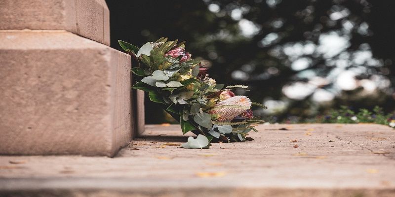 Memorial flower arrangement resting at the base of a stone monument in a peaceful outdoor setting