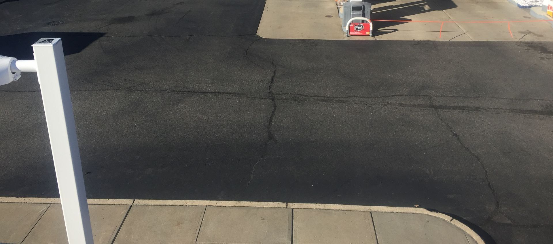A white pole is in the middle of a parking lot.