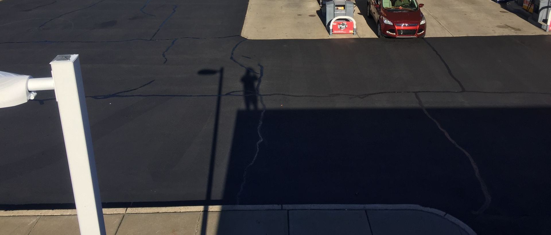 An aerial view of a gas station with a red car parked in the parking lot.