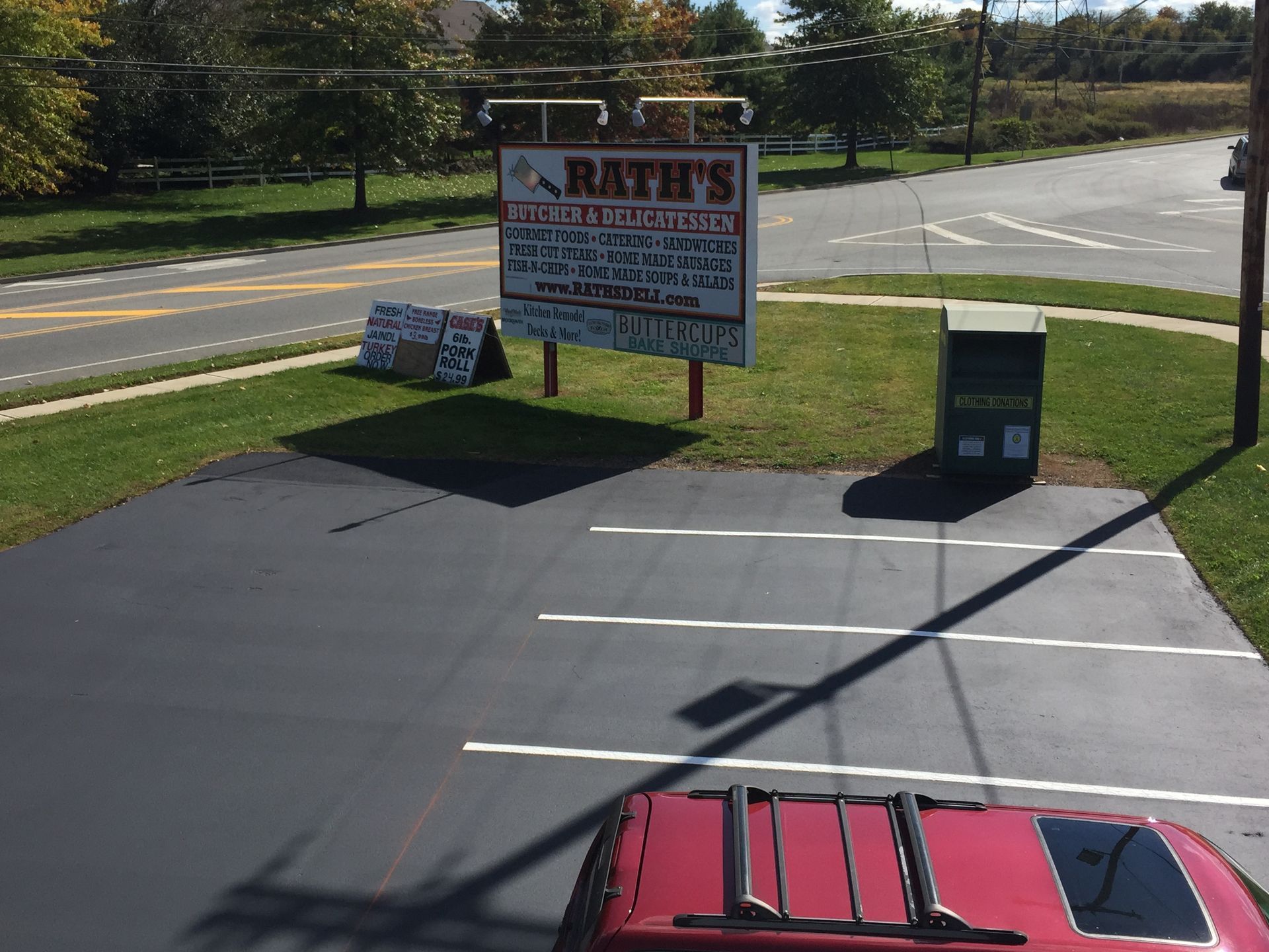A red car is parked in front of a sign for rath 's