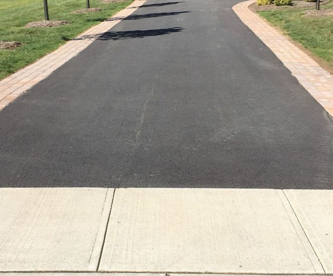 A black asphalt road with a sidewalk on the side of it.