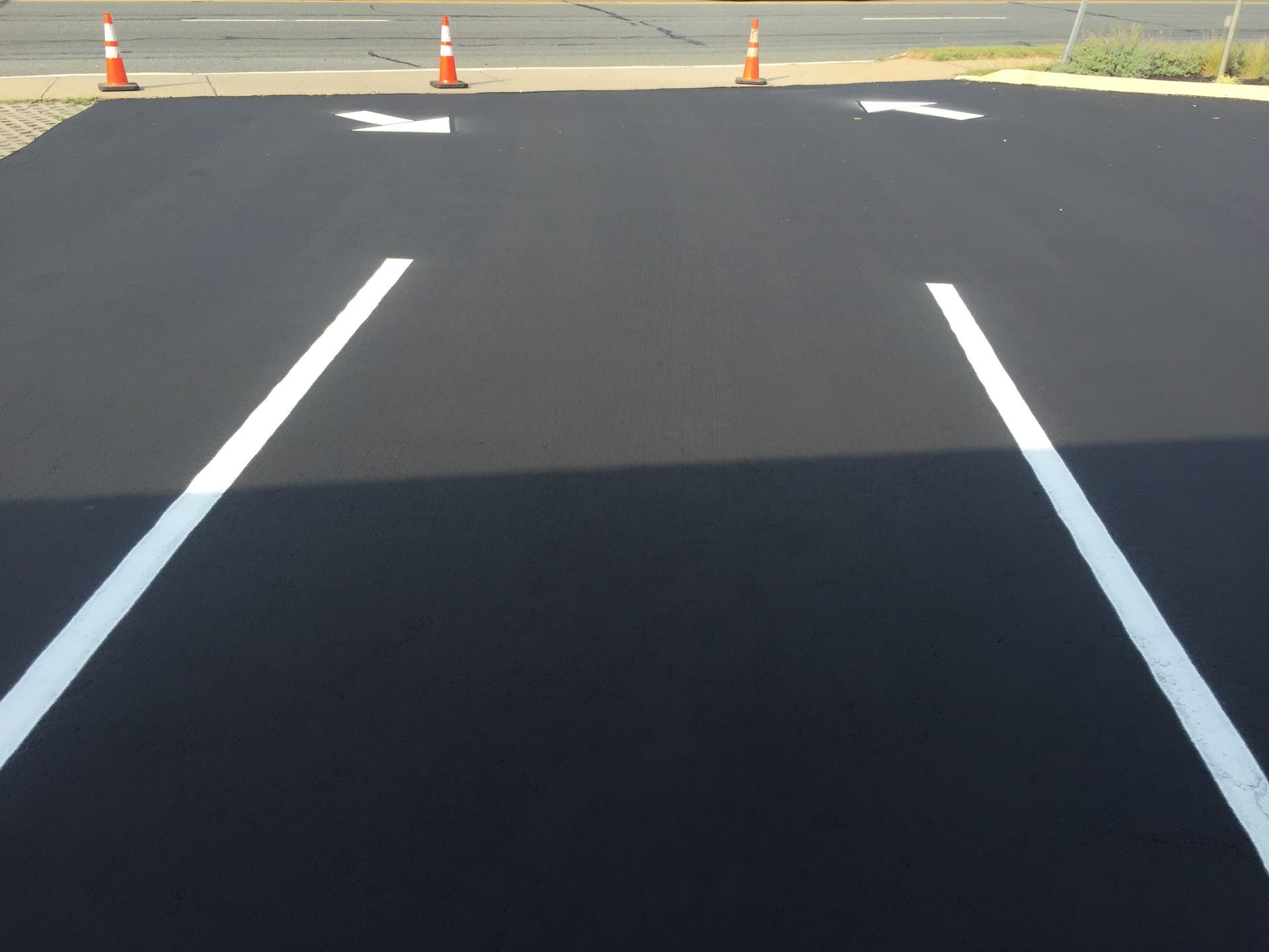 A parking lot with two white lines and an arrow painted on it