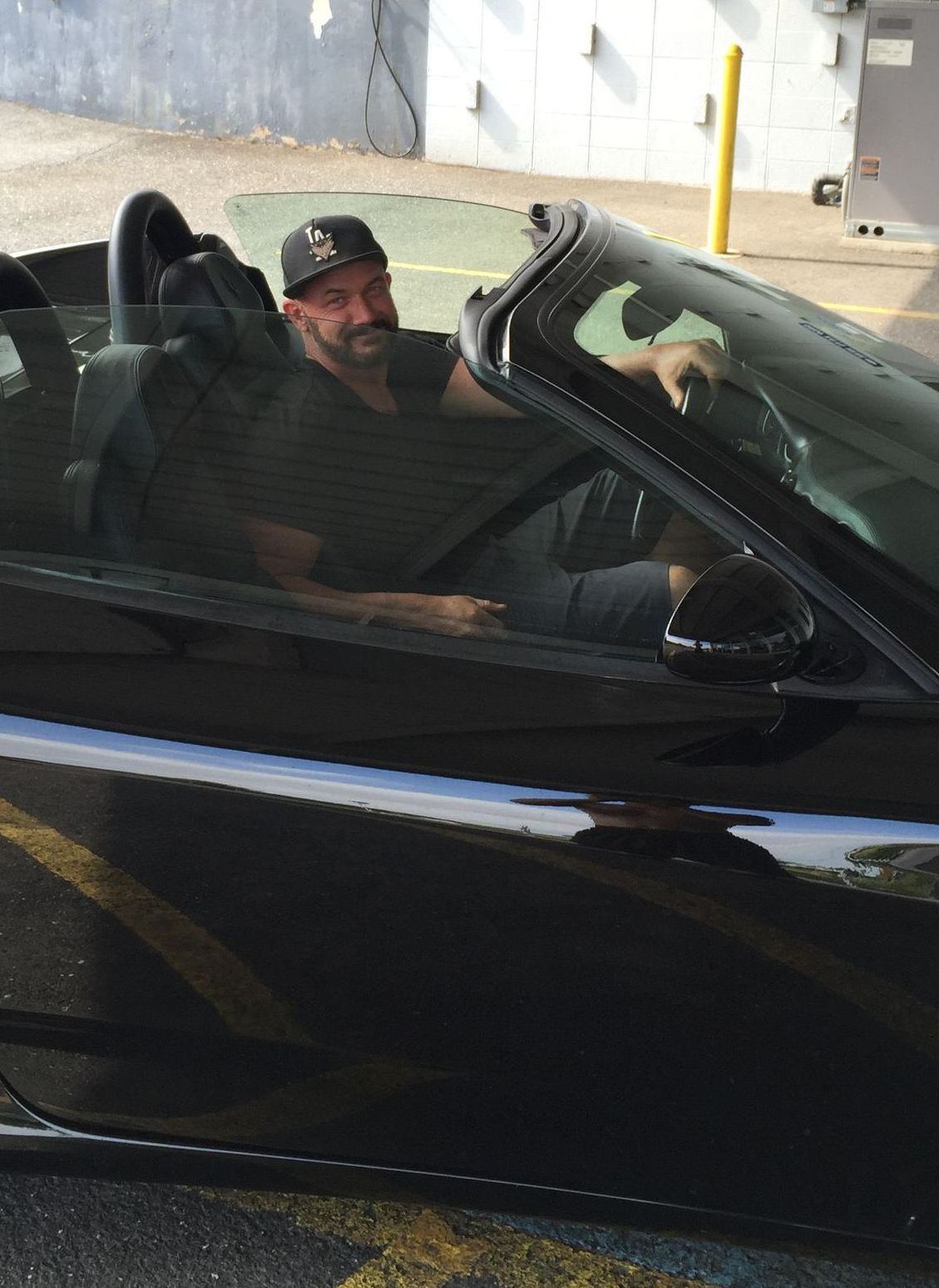 A man is sitting in a black convertible car