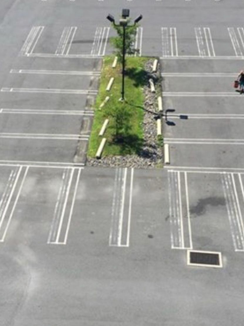 An aerial view of a parking lot with a tree in the middle