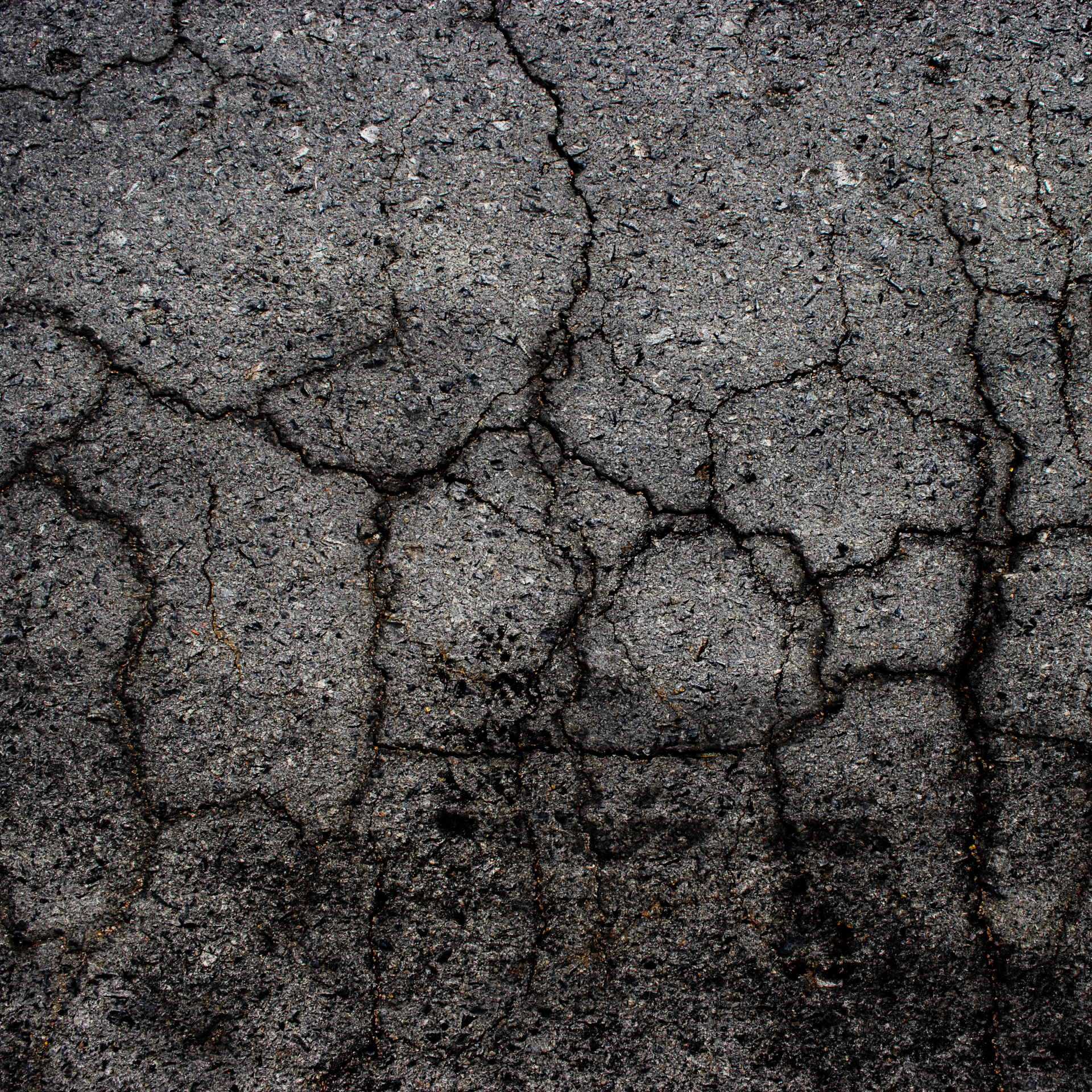 A close up of a cracked asphalt road.