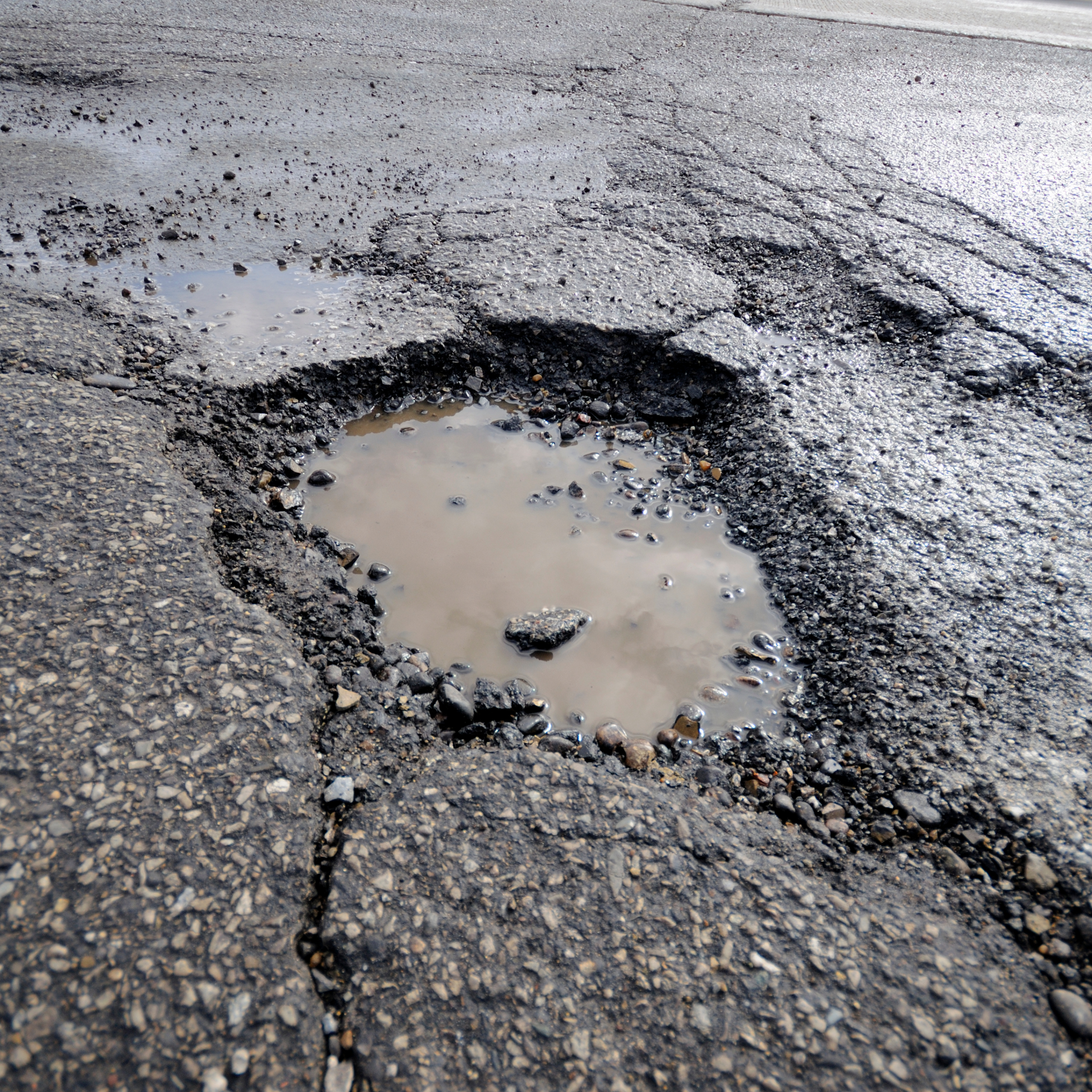 A pothole in the road with a puddle of water in it