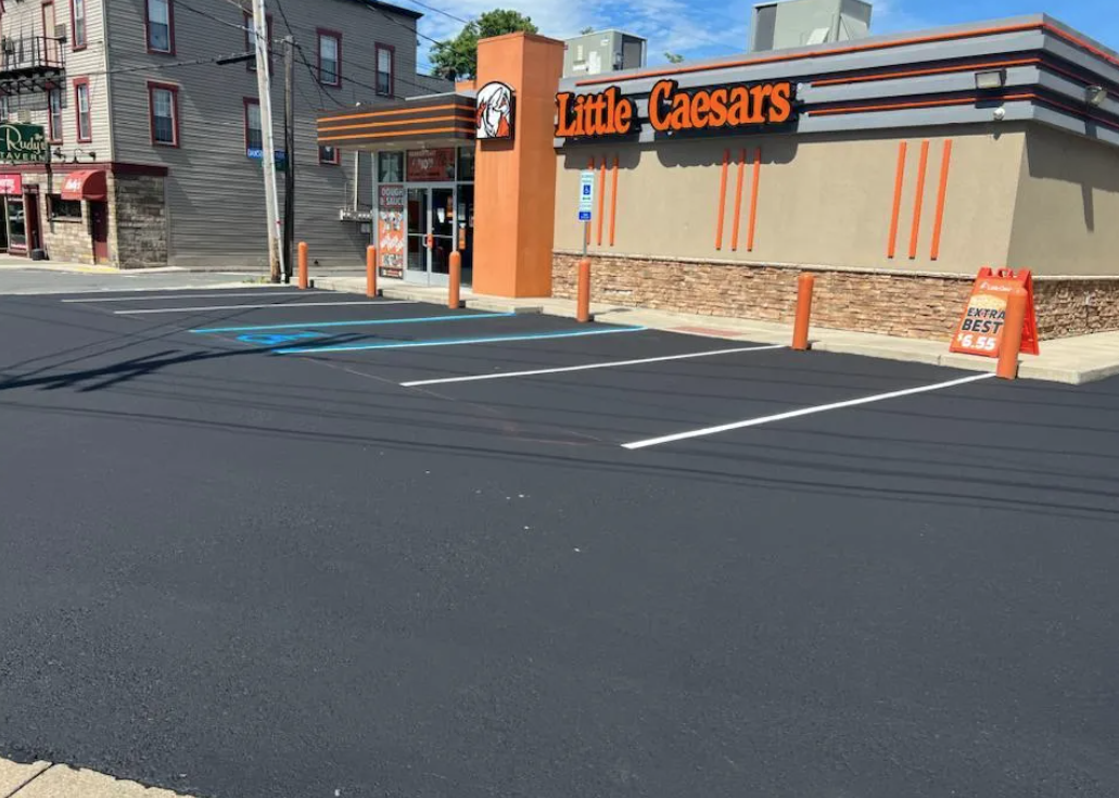 A little caesars restaurant with a parking lot in front of it