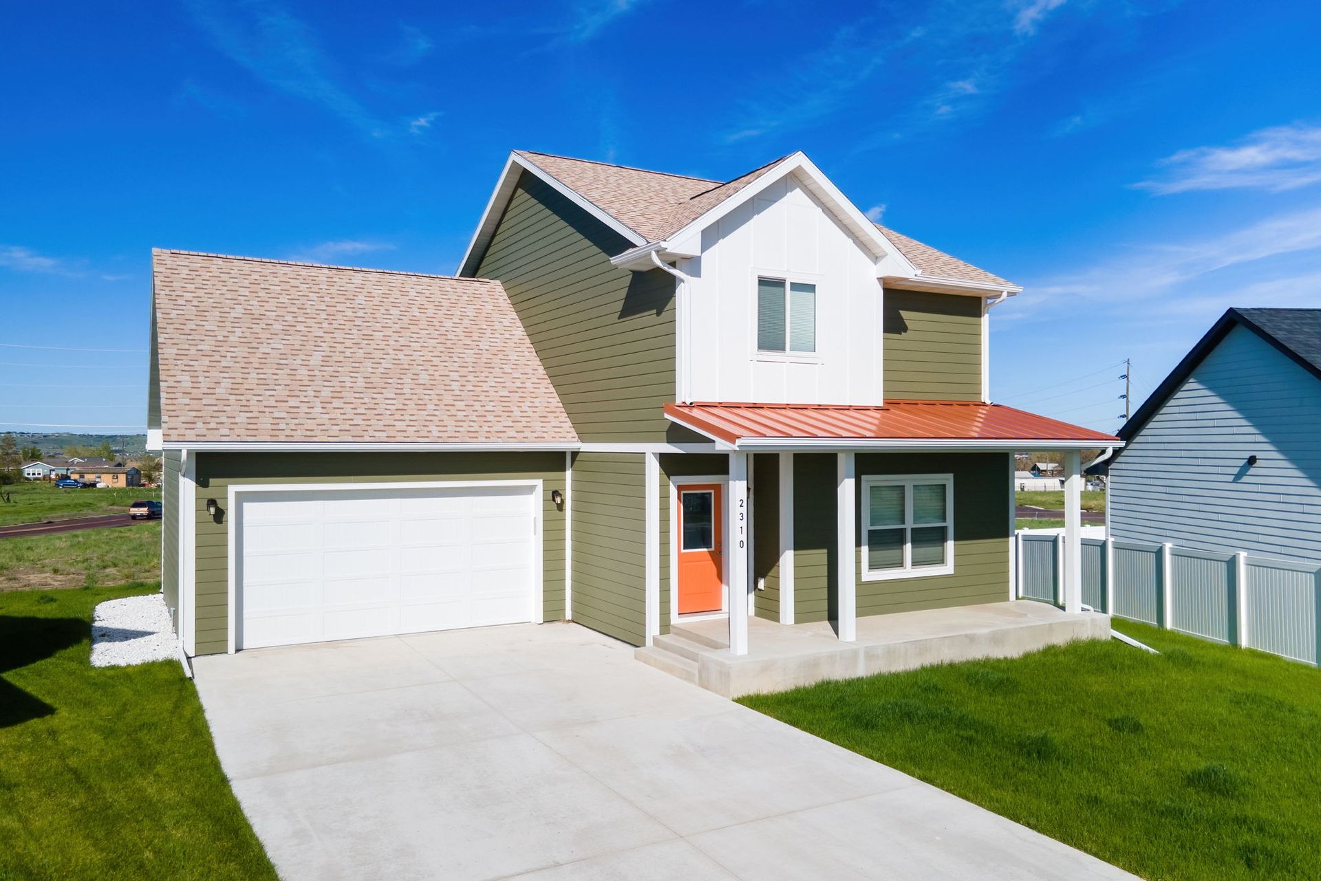 A house with a garage and a porch on a sunny day.