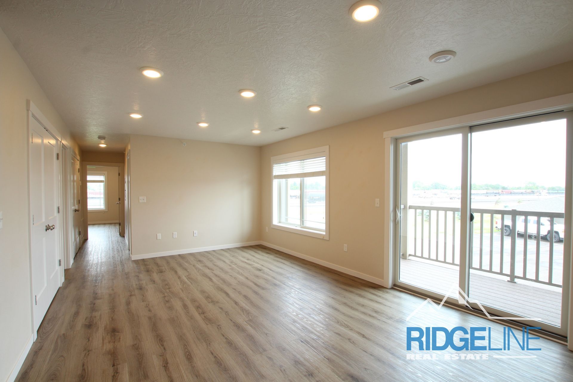 An empty living room with sliding glass doors and a balcony.