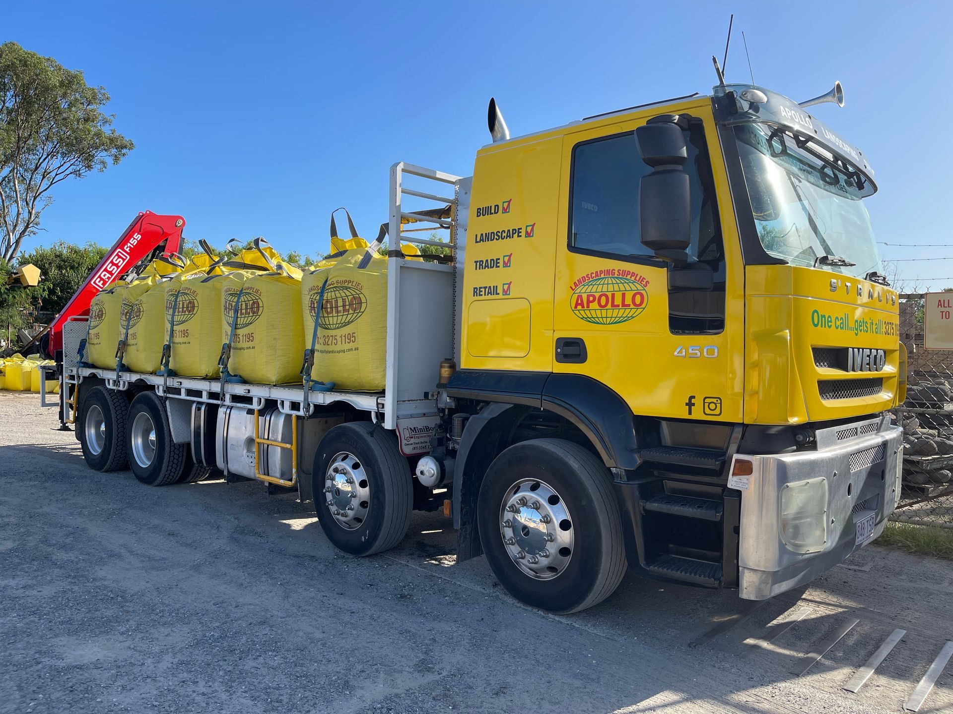 Yellow truck carrying large yellow bags under a blue sky.