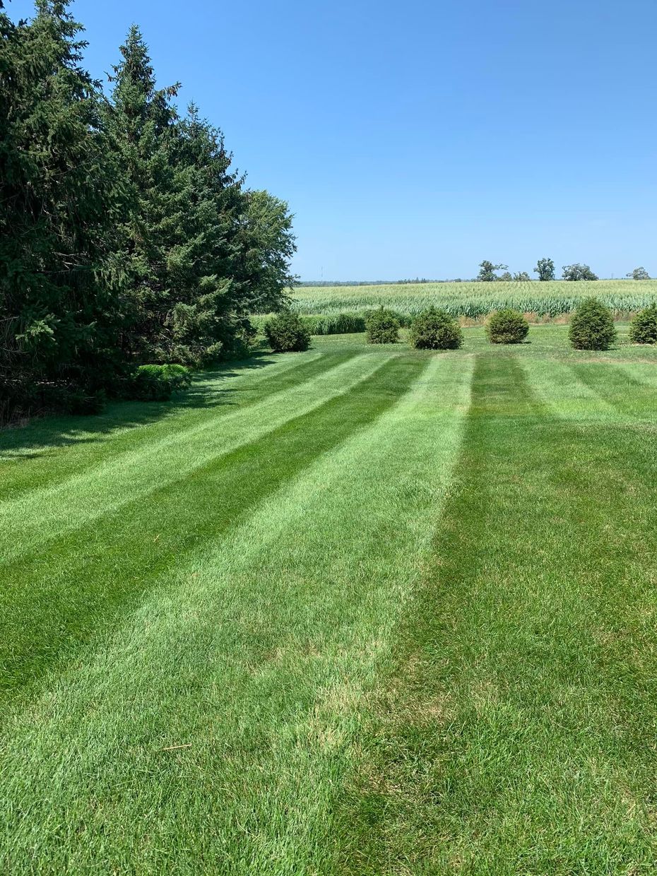 A man is riding a lawn mower on a lush green field.