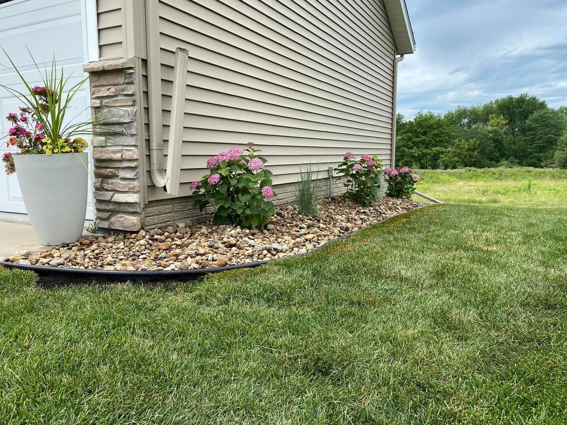 A lawn with flowers and rocks in front of a house.