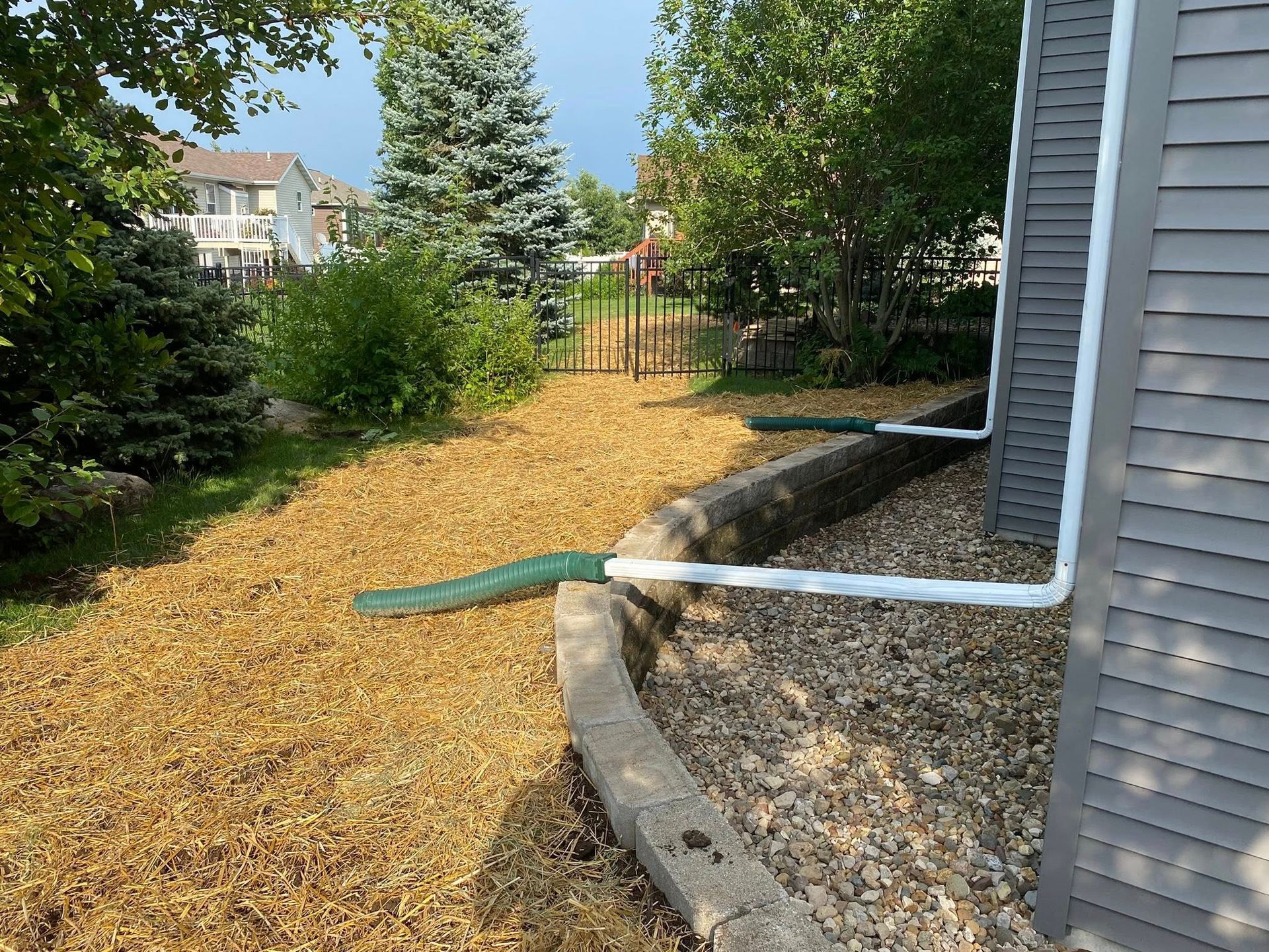A hose is connected to a pipe on the side of a house.