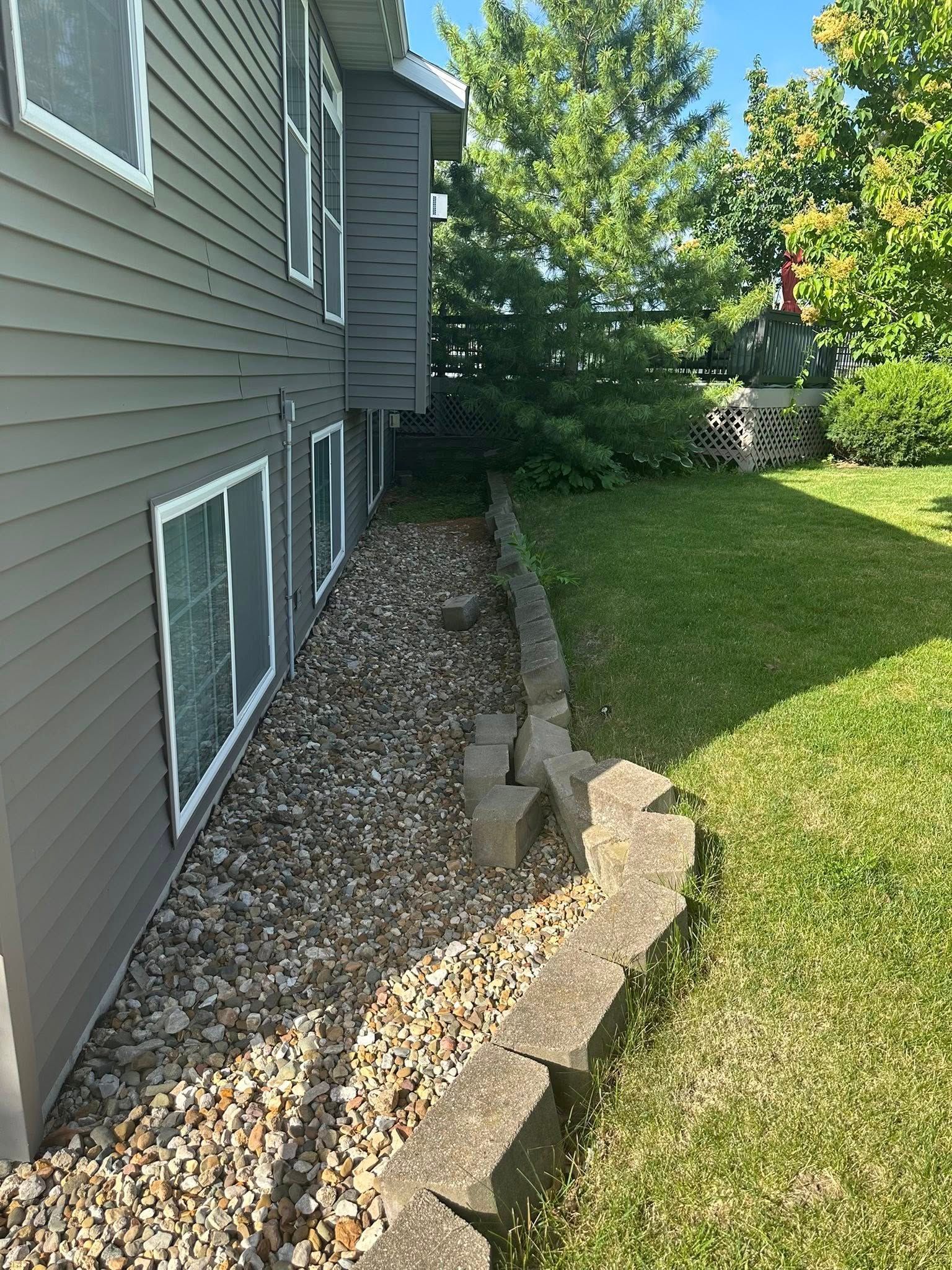 A house with a lot of windows and a rock wall in front of it.