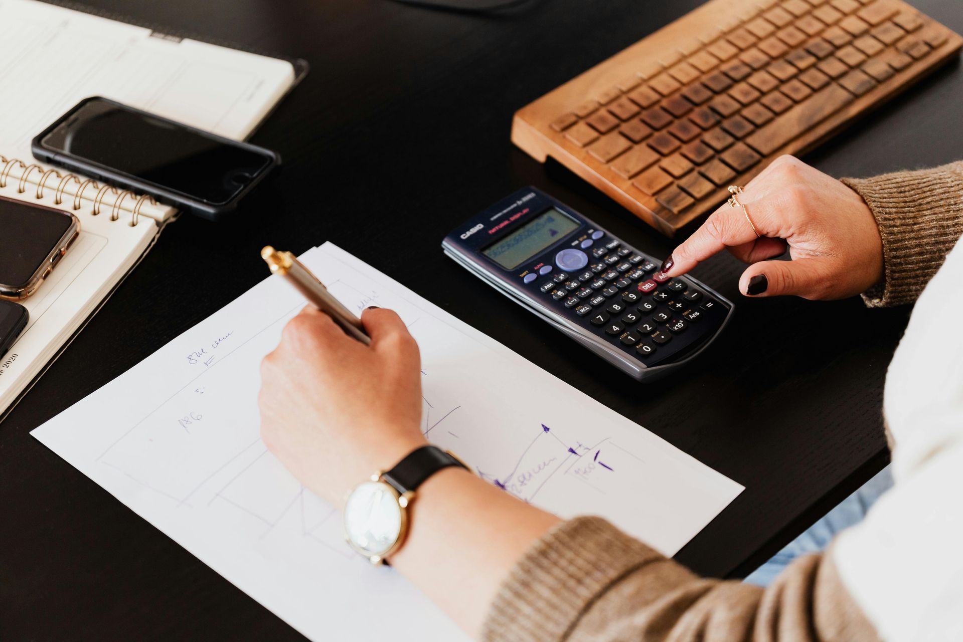 A person is using a calculator and writing on a piece of paper.