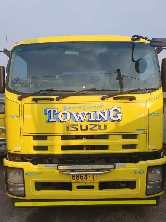 A yellow towing truck is parked in a parking lot