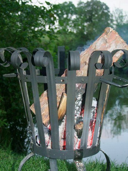 A wrought iron fire pit filled with logs and coals