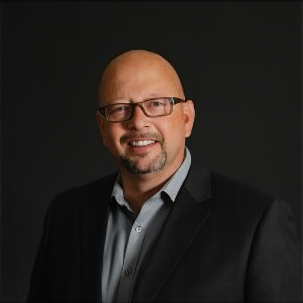 A man is holding a dog in his arms and the dog is wearing a sweater.