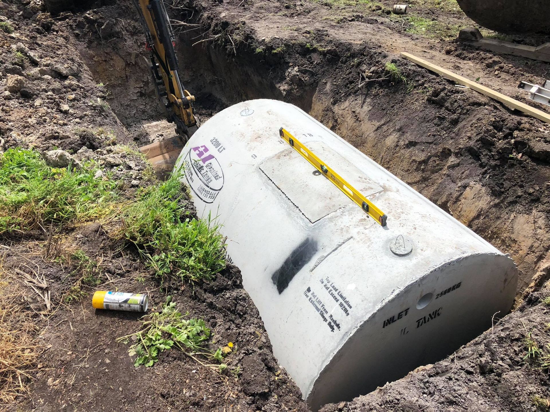 A concrete septic tank being installed in a trench, with a level on top.