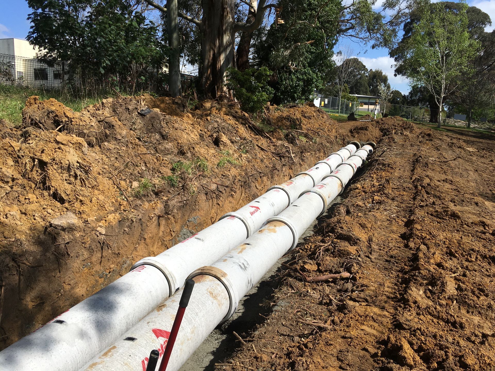 Pressure gauge with a black frame and blue and white dial attached to pipes in an industrial setting.