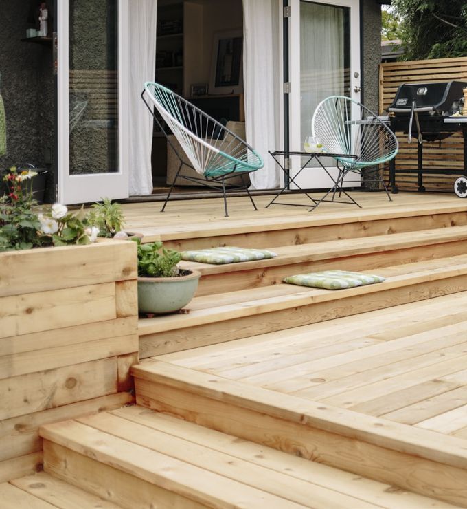 A wooden deck with chairs and a grill on it