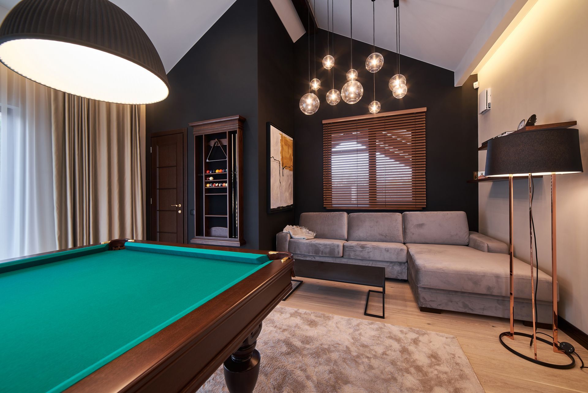 A pool table is in a living room next to a couch.
