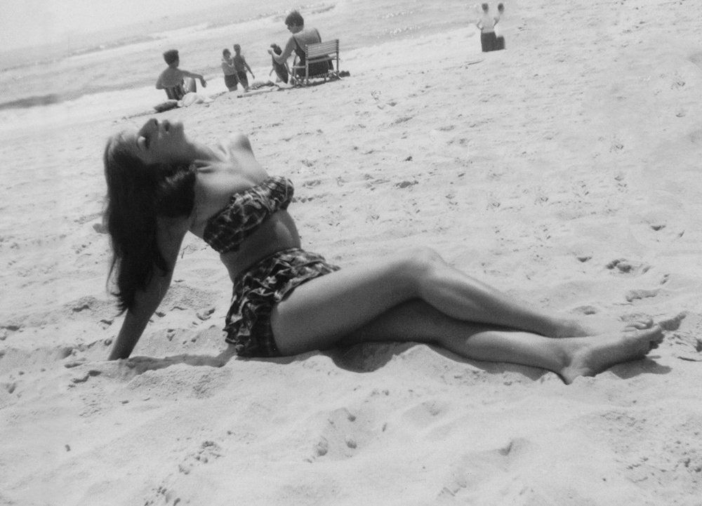 Streisand posing on the beach as a teenager.